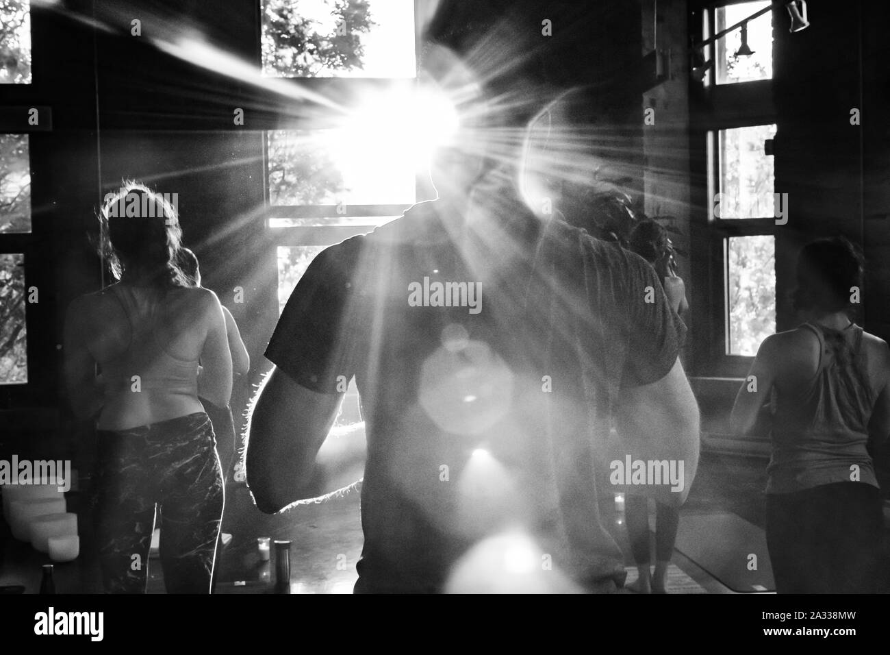 A black and white view from the rear of a gymnasium during a popular yogic session of 108 sun salutations, performed during summer & winter solstice. Stock Photo