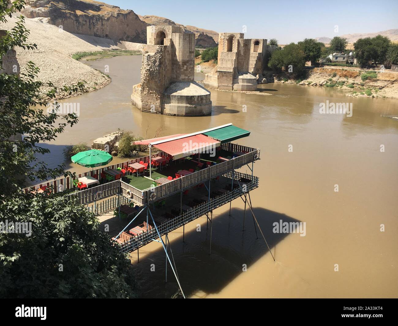 09 September 2019, Turkey, Hasankeyf: A picturesque cafe and centuries-old  bridge piers are located on the Tigris River. The village lies in a unique  cultural landscape on the Tigris. People have been
