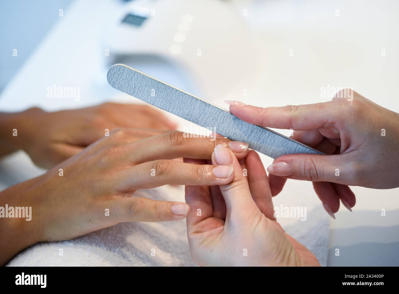 Woman in a nails salon receiving a manicure with nail file Stock Photo