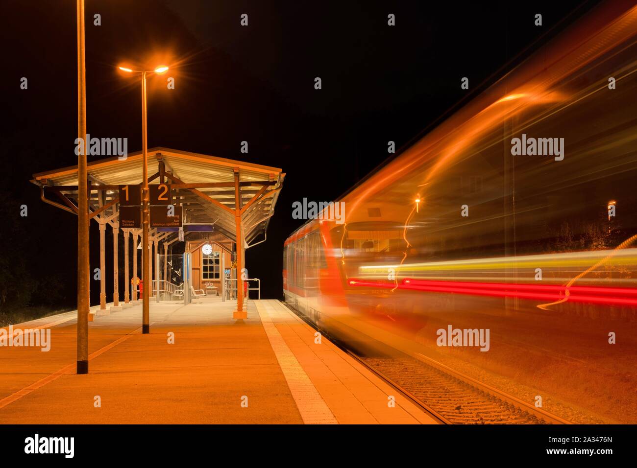 Railway station at night with moving train, Hartenstein, Saxony, Germany Stock Photo