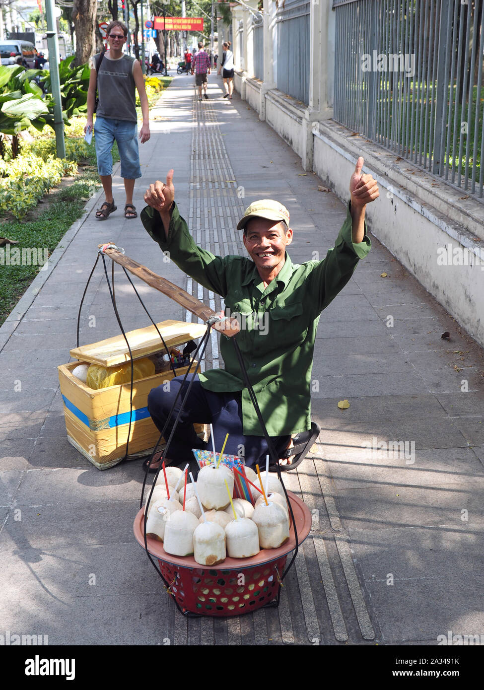 HANOI, VIETNAM, DECEMBER 15, 2014 : A peddler carrying a traditional balance is selling coconuts in the streets of Hanoi, Vietnam Stock Photo