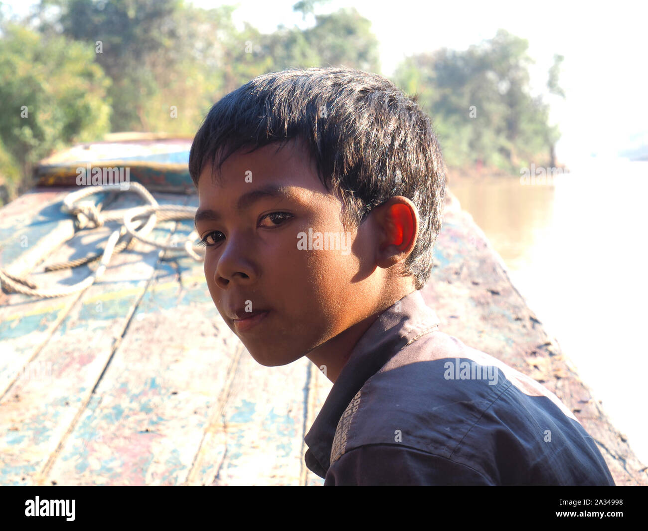 poor cambodian boy working on a boat in floating village Stock Photo