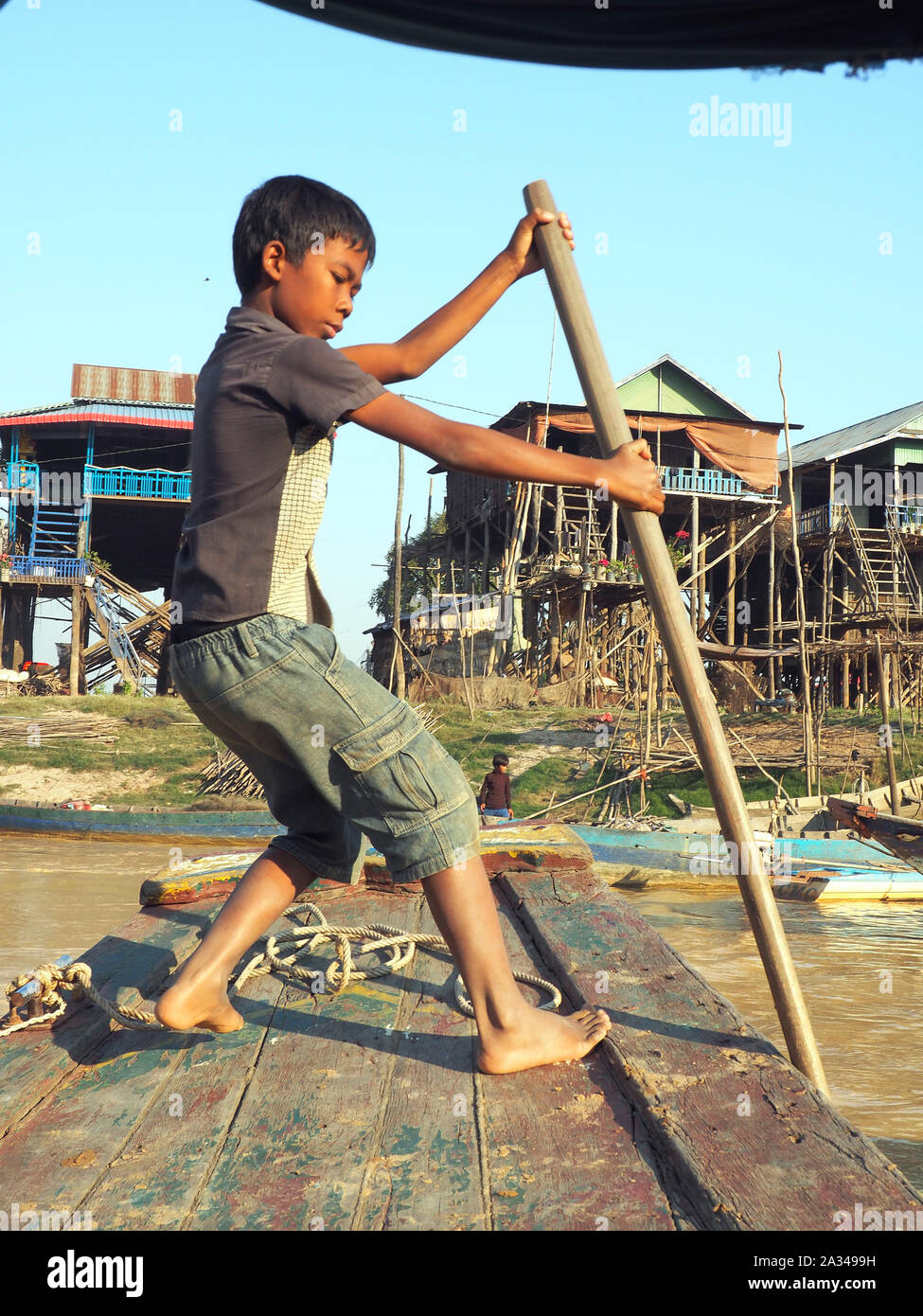 poor cambodian boy working on a boat in floating village Stock Photo