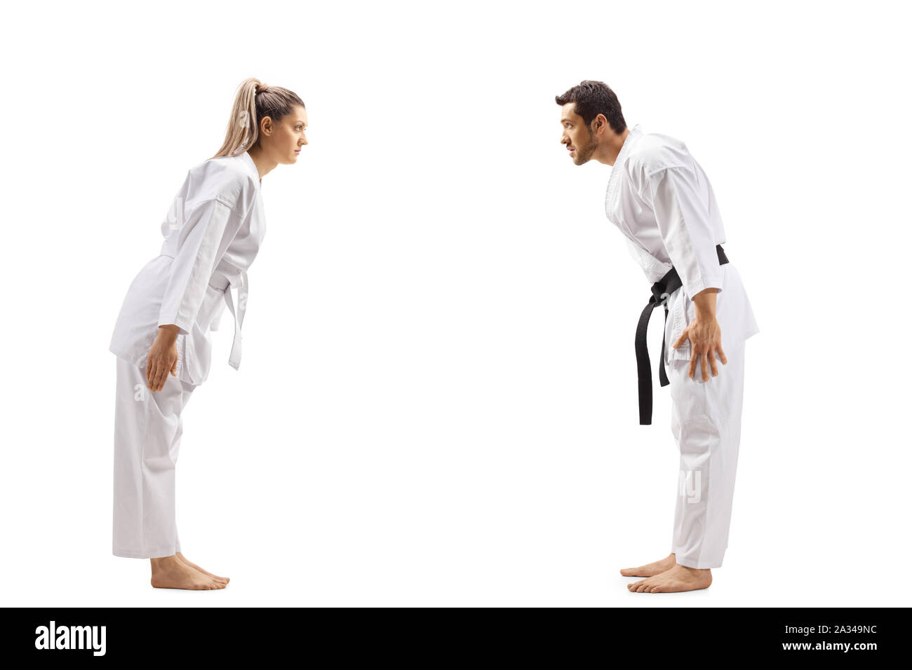 Full length profile shot of a woman with white belt in karate and a man with black belt bowing at each other isolated on white background Stock Photo