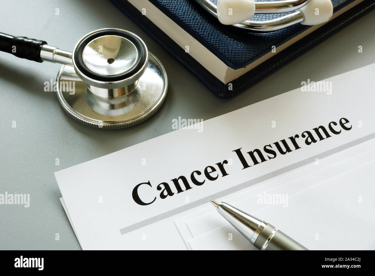 Cancer Insurance policy and stethoscope on a desk. Stock Photo