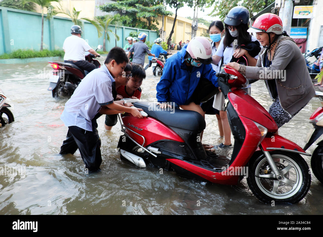 HO CHI MINH CITY, VIET NAM, little boys help woman push motorbike that