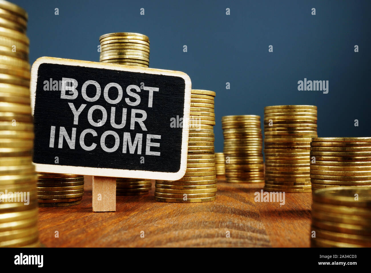 Boost Your Income concept. Stacks of coins and wooden plate. Stock Photo