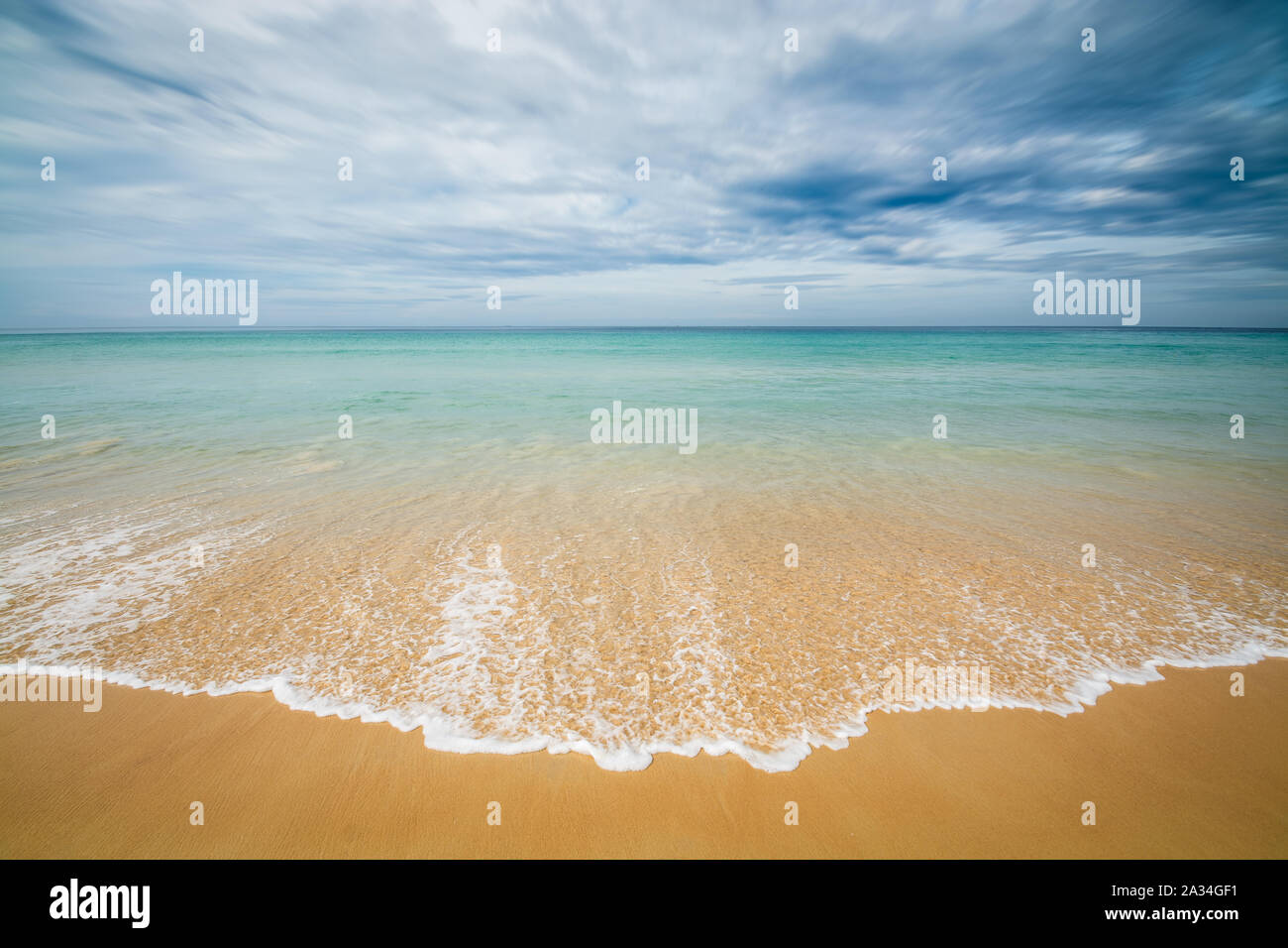 Sea and beach with dramatic cloudy blue sky Stock Photo - Alamy