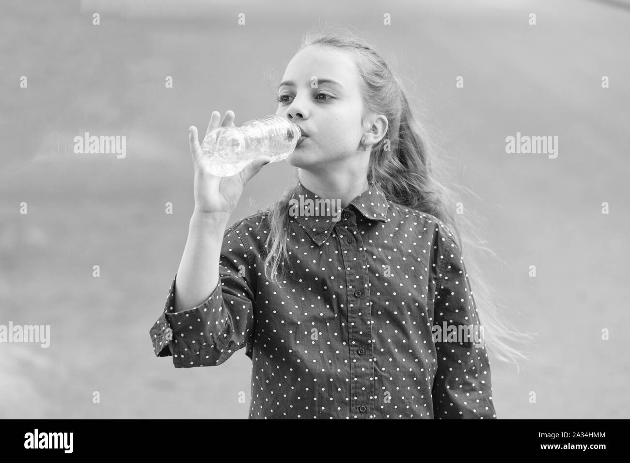 Water is life. Thirsty child drinking fresh water from plastic bottle. Little girl having a drink from water bottle. Quenching thirst with natural mineral clean water. Stock Photo