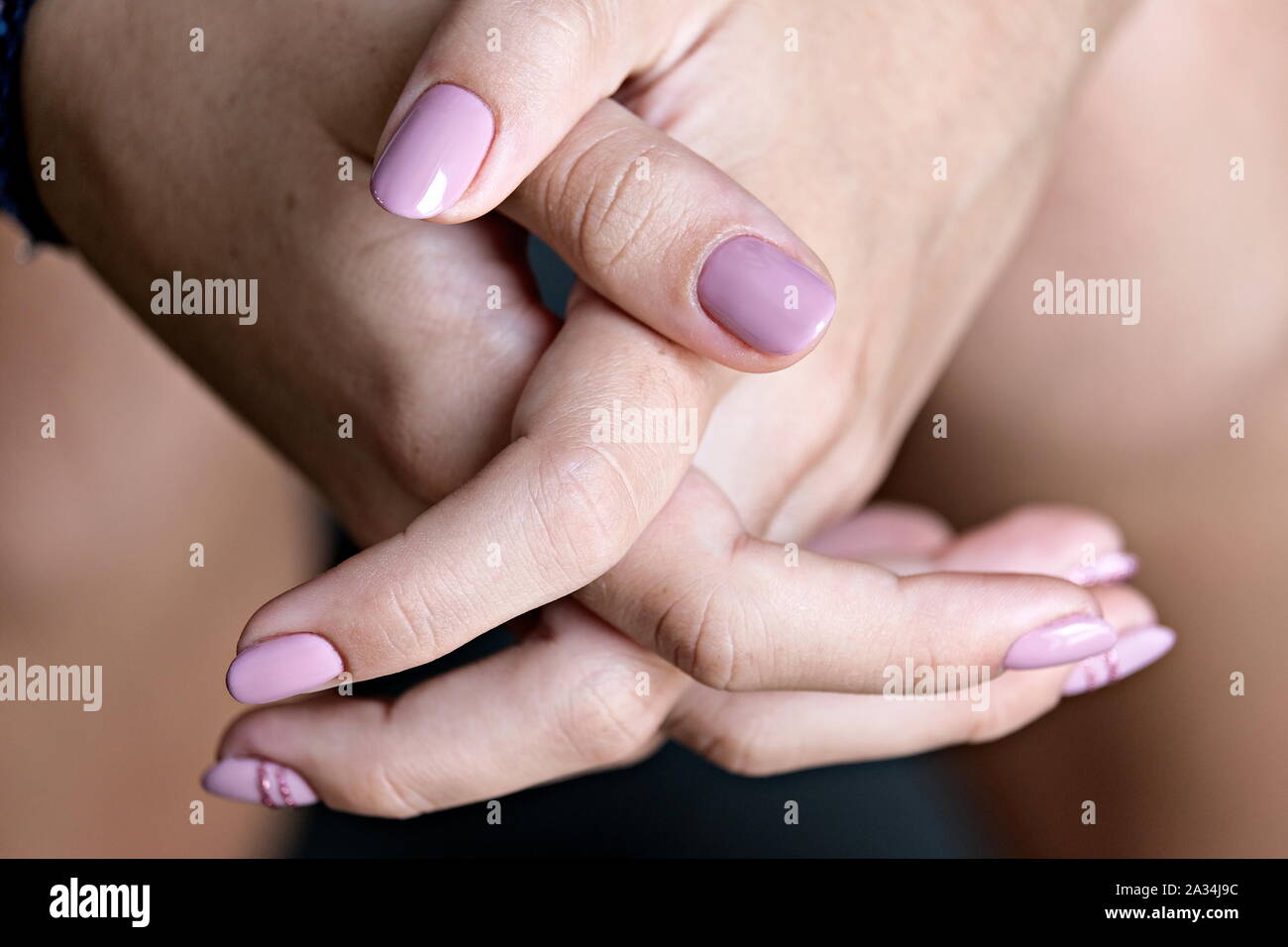 Close view of the clasped hands of a young woman Stock Photo