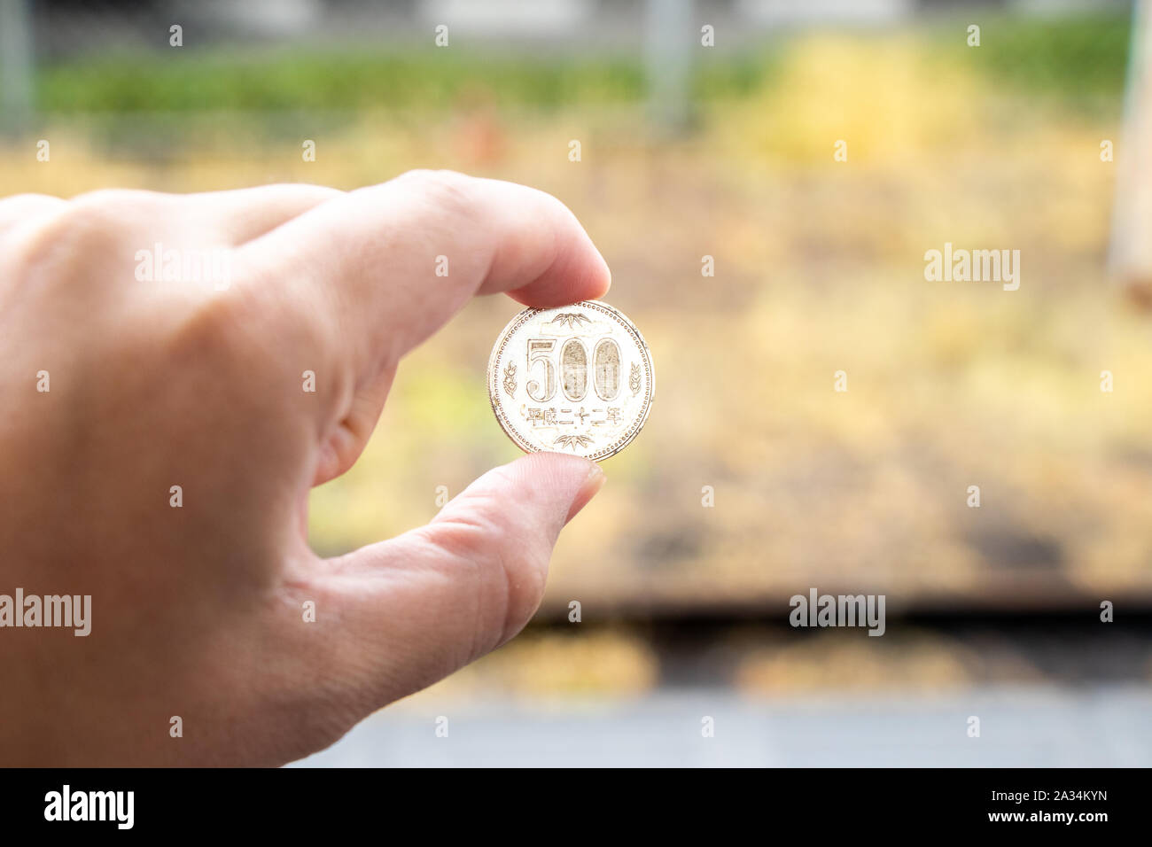 Man hold japanese coin 500 yen on blurred background Stock Photo