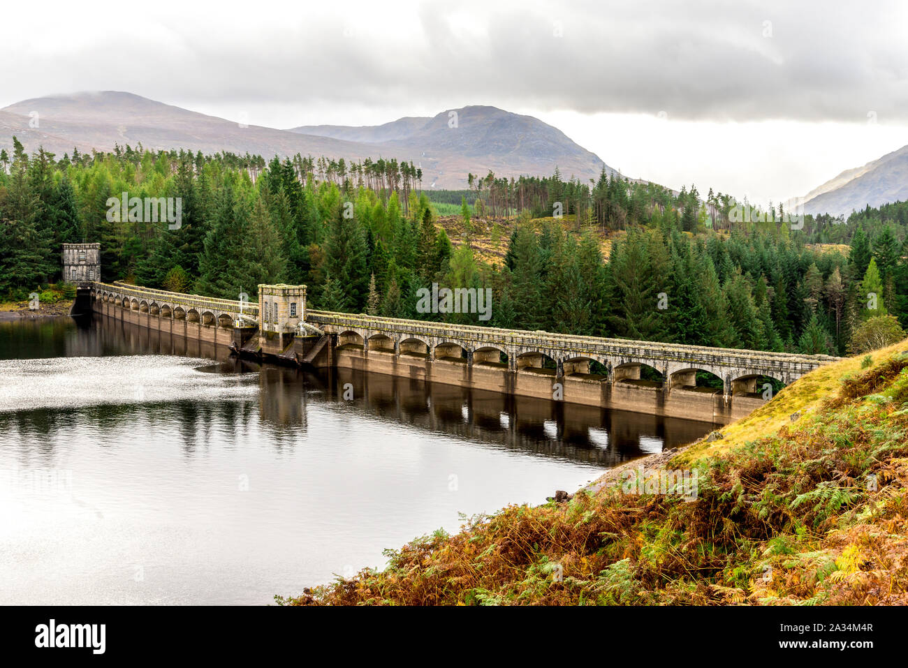 A scenic view of arch curved Laggan Dam with Scottish Highlands in background, Scotland Stock Photo