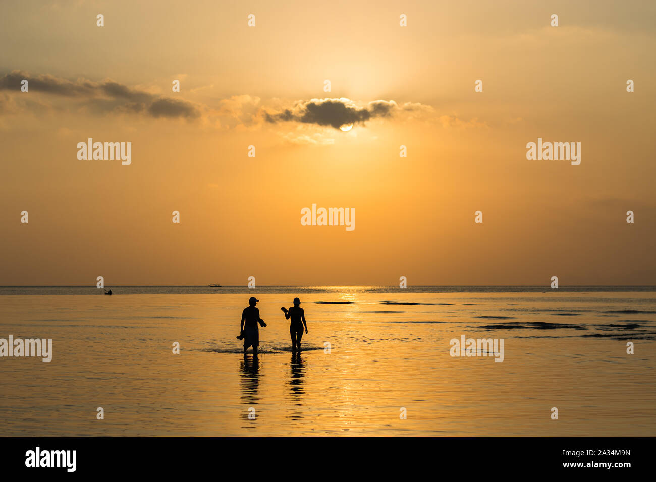 Silhouette couple walking in the sea under sunlight with warm tone ...
