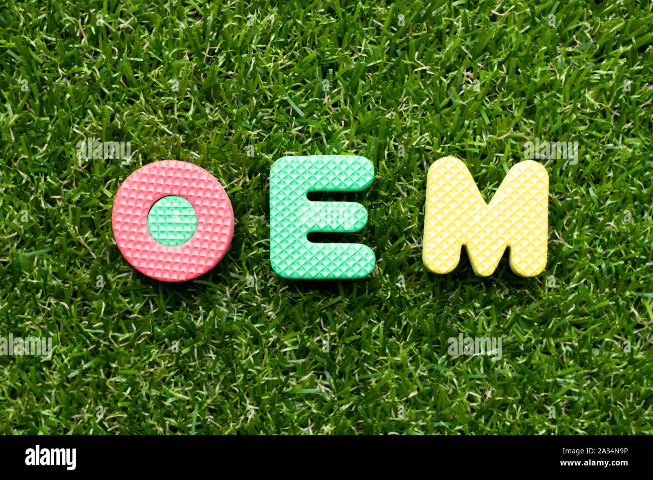 Toy foam letter in word OEM (Abbreviation of Original Equipment Manufacturer) on green grass background Stock Photo