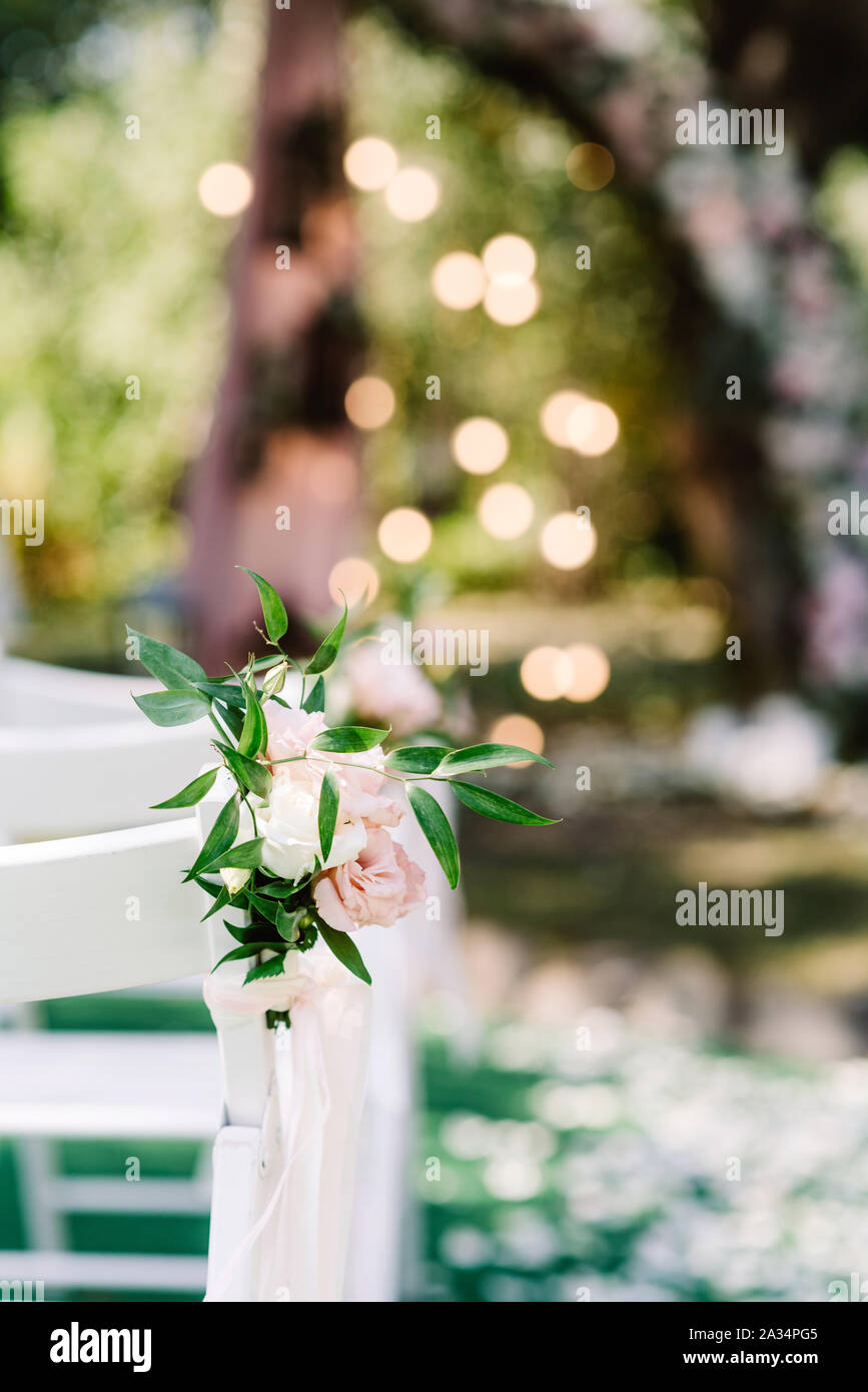 Stylish little boutoniere of natural colors and greens against a blurred  background. Decorated chairs for guests at the wedding Stock Photo - Alamy