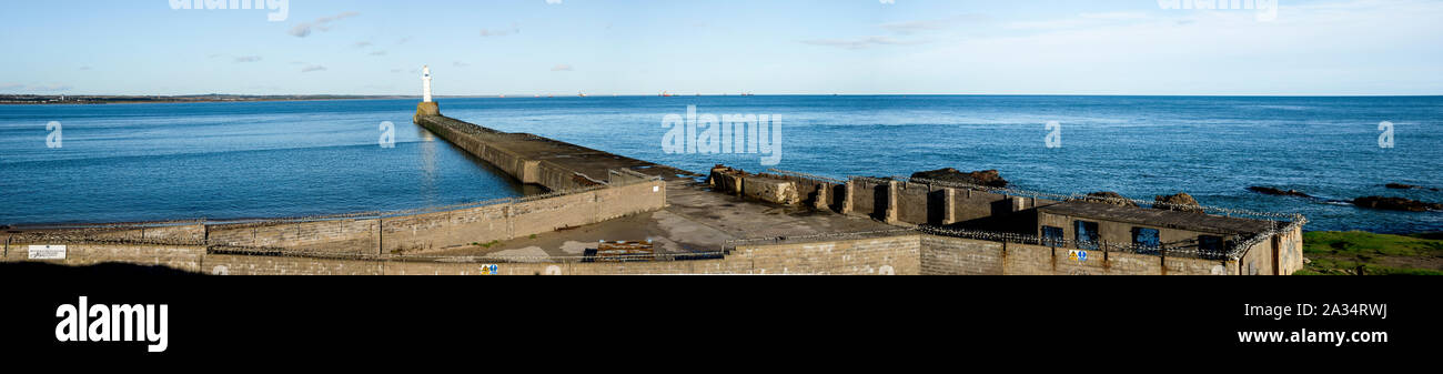 South breakwater lighthouse and a  barbed wire brick wall preventing entrance to public, Aberdeen, Scotland Stock Photo
