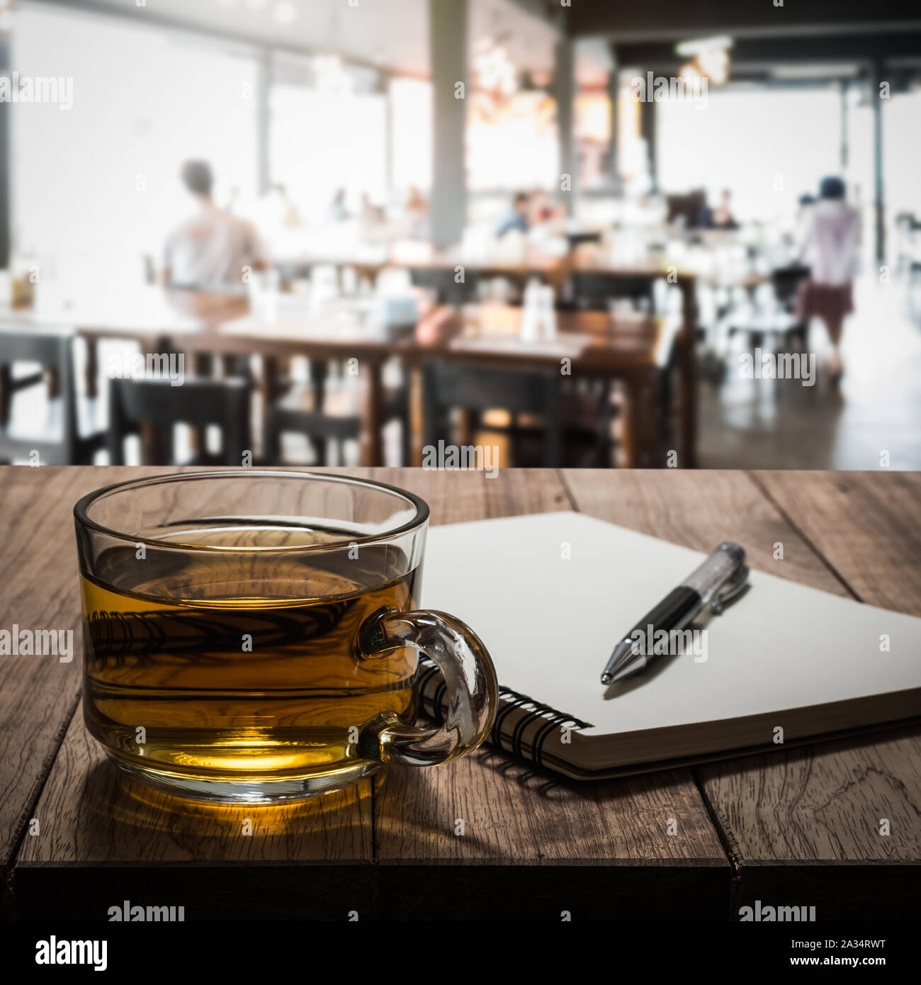 Hot tea with notebook and pen on wooden table in the coffee shop Stock Photo