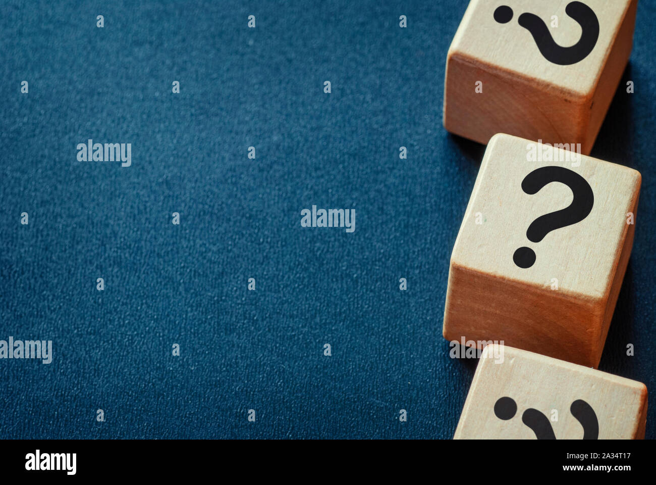 Side border of question marks on wooden cubes over a dark blue textured ...