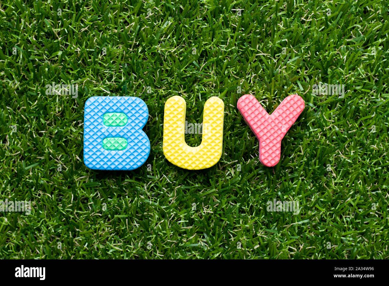 Toy foam letter in word buy on green grass background Stock Photo