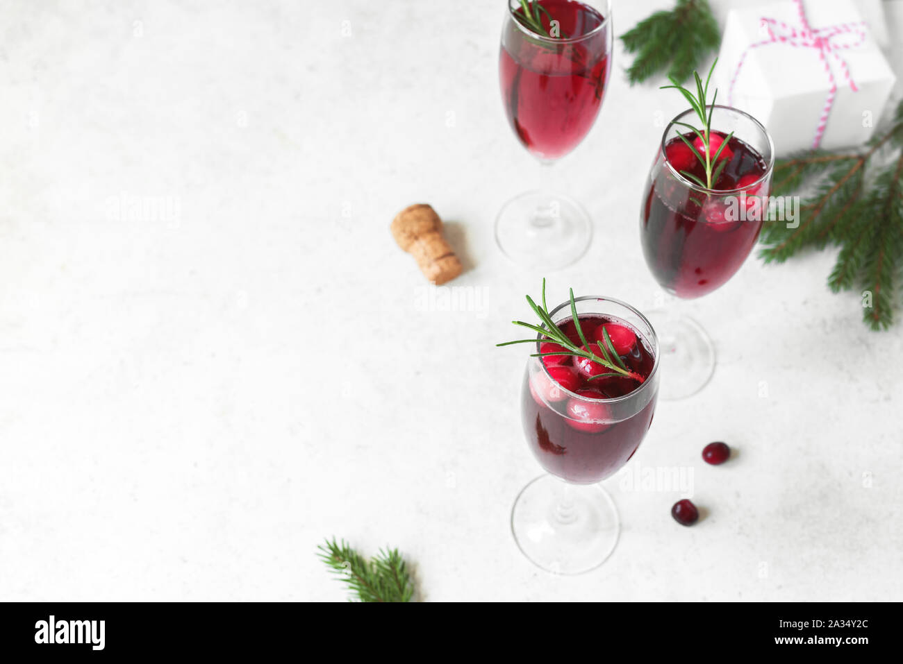 Cranberry mimosa with rosemary and christmas decor on white background, copy space. Cocktail with champagne for Christmas morning. Stock Photo
