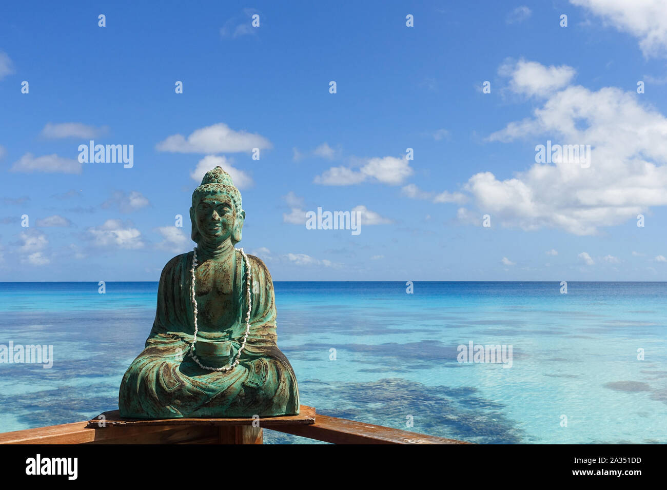 A sculpture of Buddha rests on a railing overlooking a tropical lagoon on the island of Fakarava in French Polynesia Stock Photo