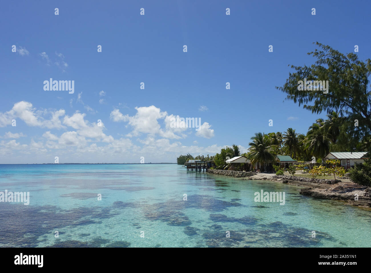 Houses and palm trees line the coast of a tropical lagoon on the island of Fakarava in French Polynesia Stock Photo