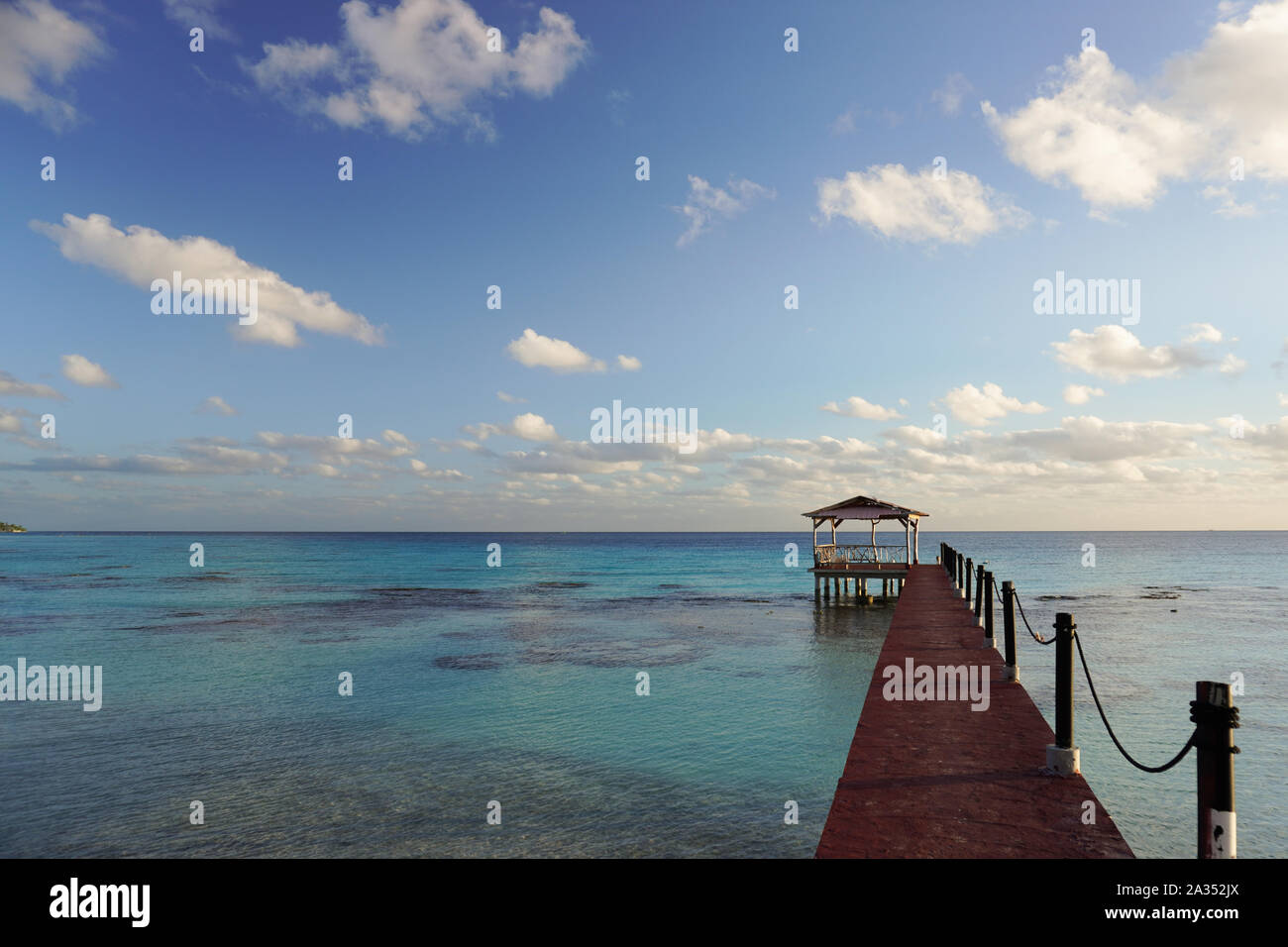 A pier leads out into a tropical lagoon under a bright blue sky on the island of Fakarava in French Polynesia Stock Photo