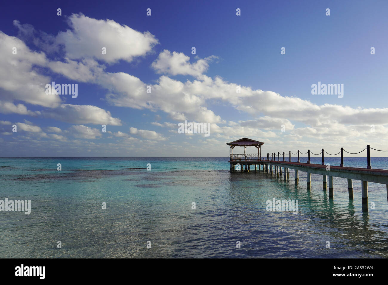 A walkway leads out to a dock over a tropical lagoon in the South Pacific Stock Photo