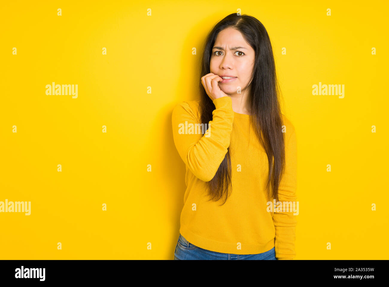 Beautiful brunette woman over yellow isolated background looking ...