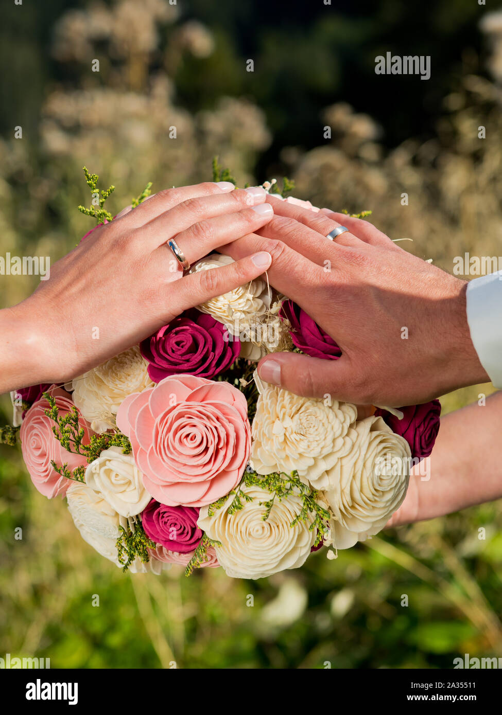 Hands of the bride and groom on the wedding bouquet Stock Photo - Alamy