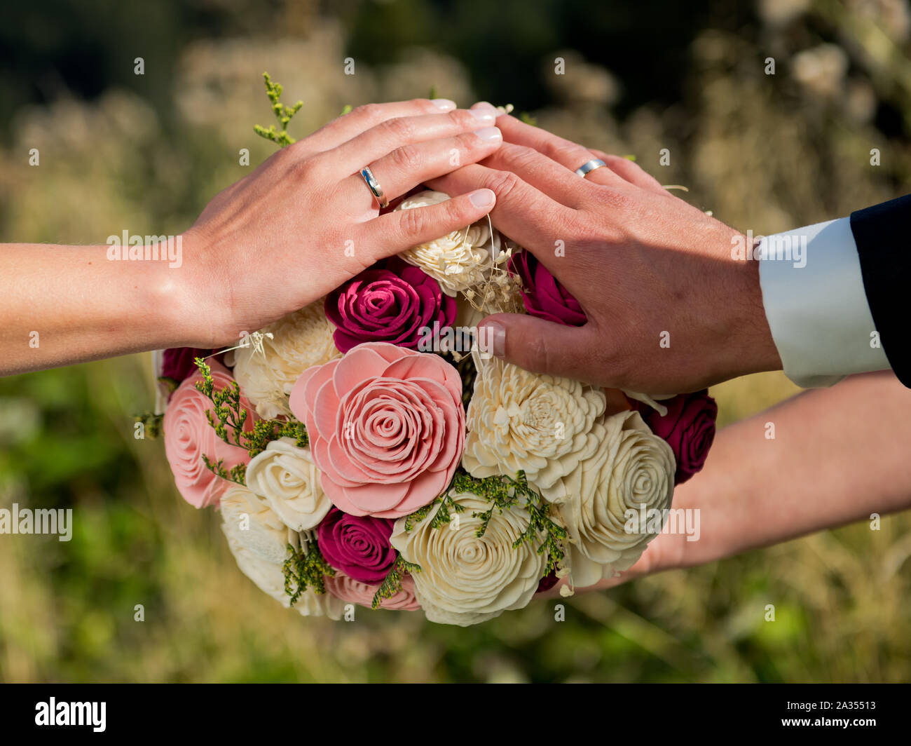 Hands of the bride and groom on the wedding bouquet Stock Photo - Alamy