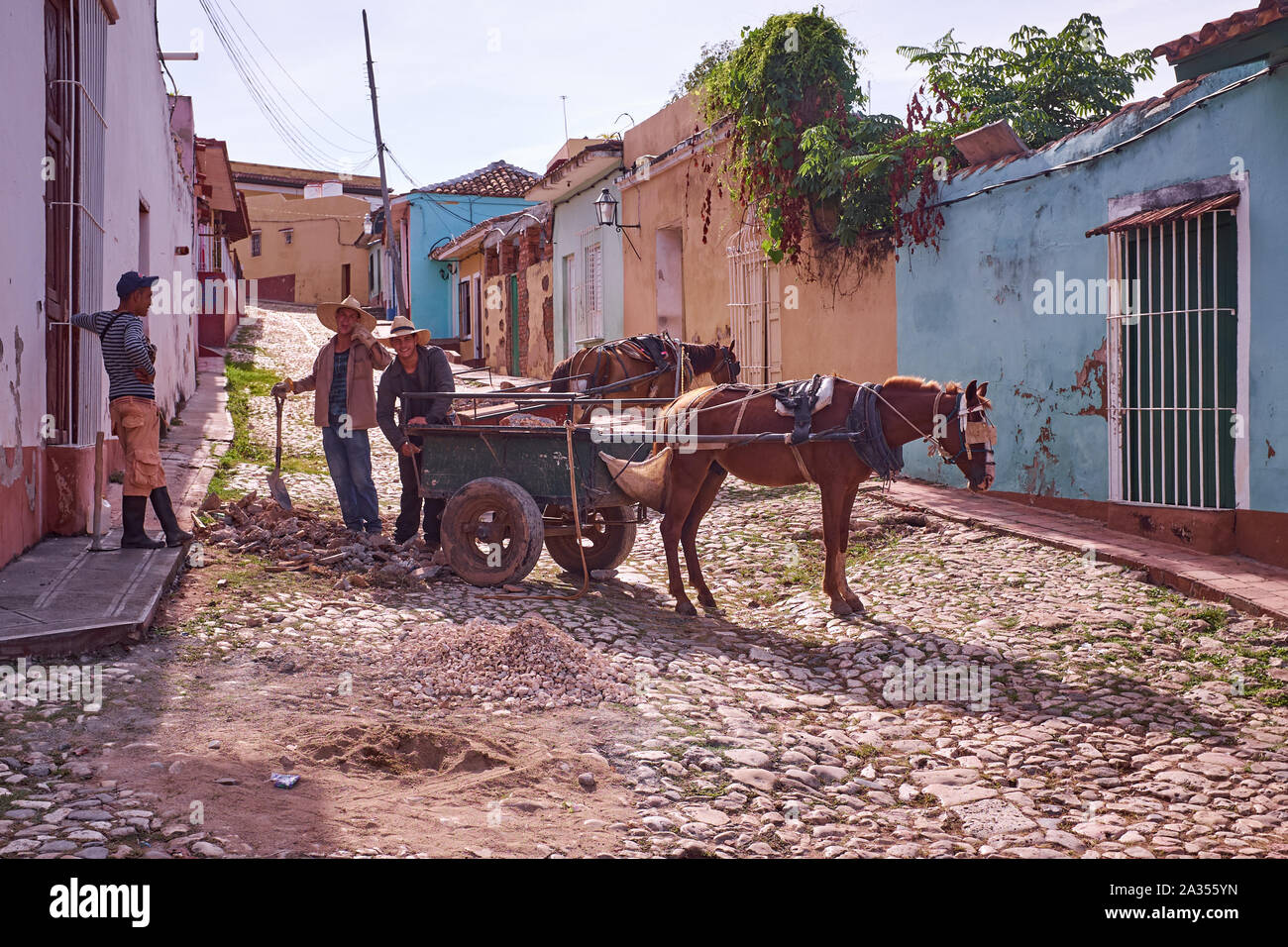 A Workhorse and workmen repair cobblestone streets in Trinidad, Cuba Stock Photo