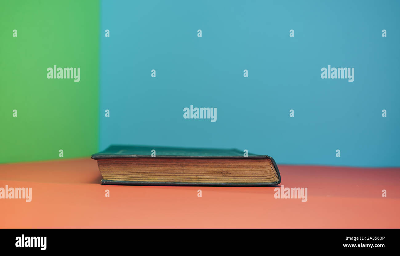 Book on a red table and green blue background. Stock Photo