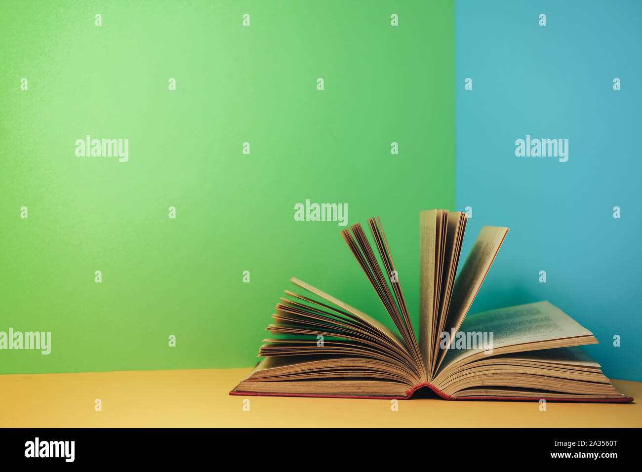 Beautiful open red book on a yellow table and green blue background ...