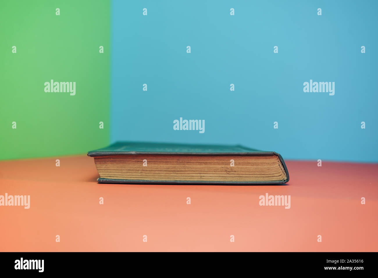 Book on a red table and green blue background. Stock Photo