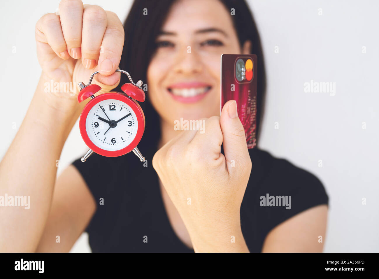 pay by credit card. woman hands holding credit card and red clock. Online shopping. Online shopping concept . Credit card and alarm clock on the white Stock Photo
