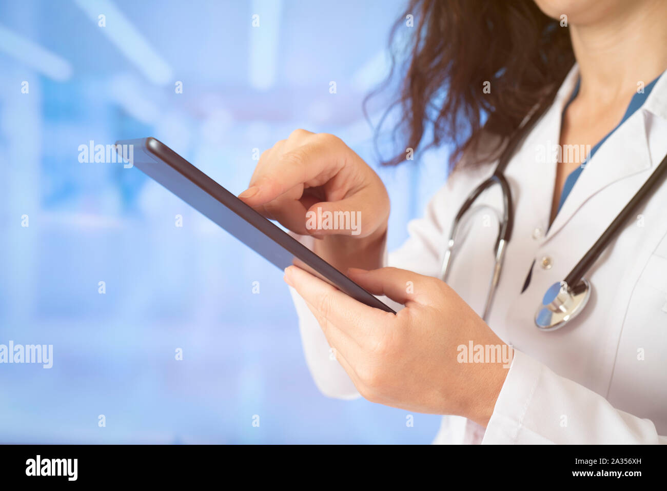 Woman doctor using tablet computer while standing straight in hospital Stock Photo