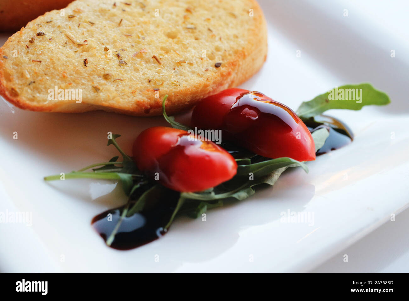 Garnish of cherry tomato with balsamic vinegar and garlic bread Stock Photo