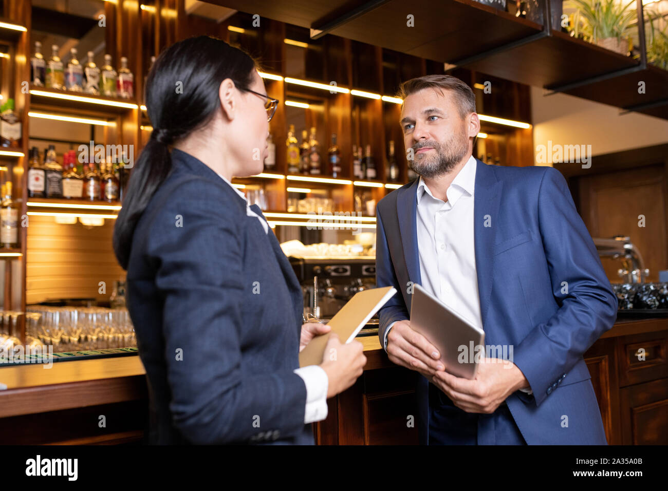 Two owners of luxurious restaurant interacting by bar counter Stock Photo