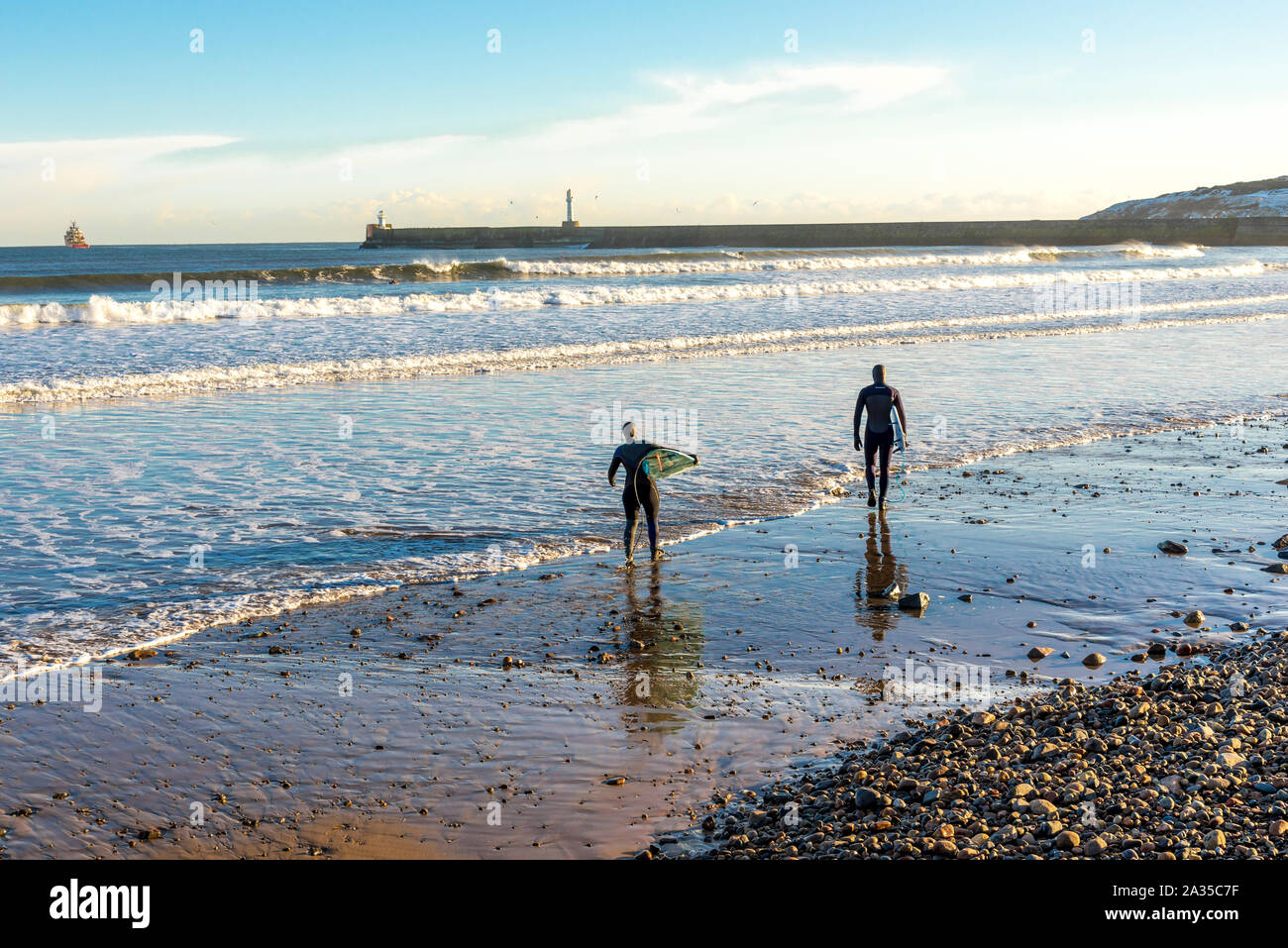 A surfers couple prepare to enter North sea with their board at Aberdeen beach, Scotland Stock Photo