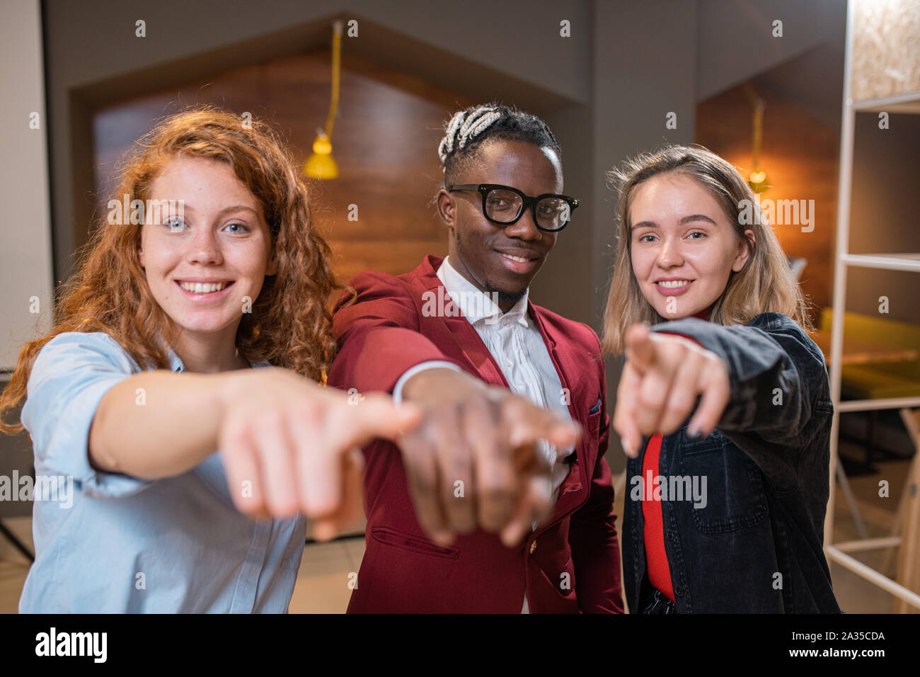 Small group of happy young multi-ethnic students in casualwear pointing at you Stock Photo