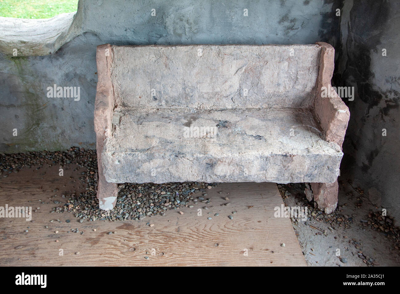 Prehistoric style bench or seat inside a stone house Stock Photo