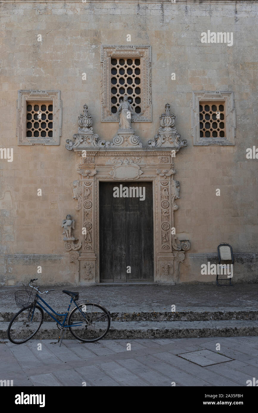 Melpignano. Greek city, View of the ancient door of the palace near the cathedral. Symmetry of the façade in Lecce stone worked with floral and symbol Stock Photo