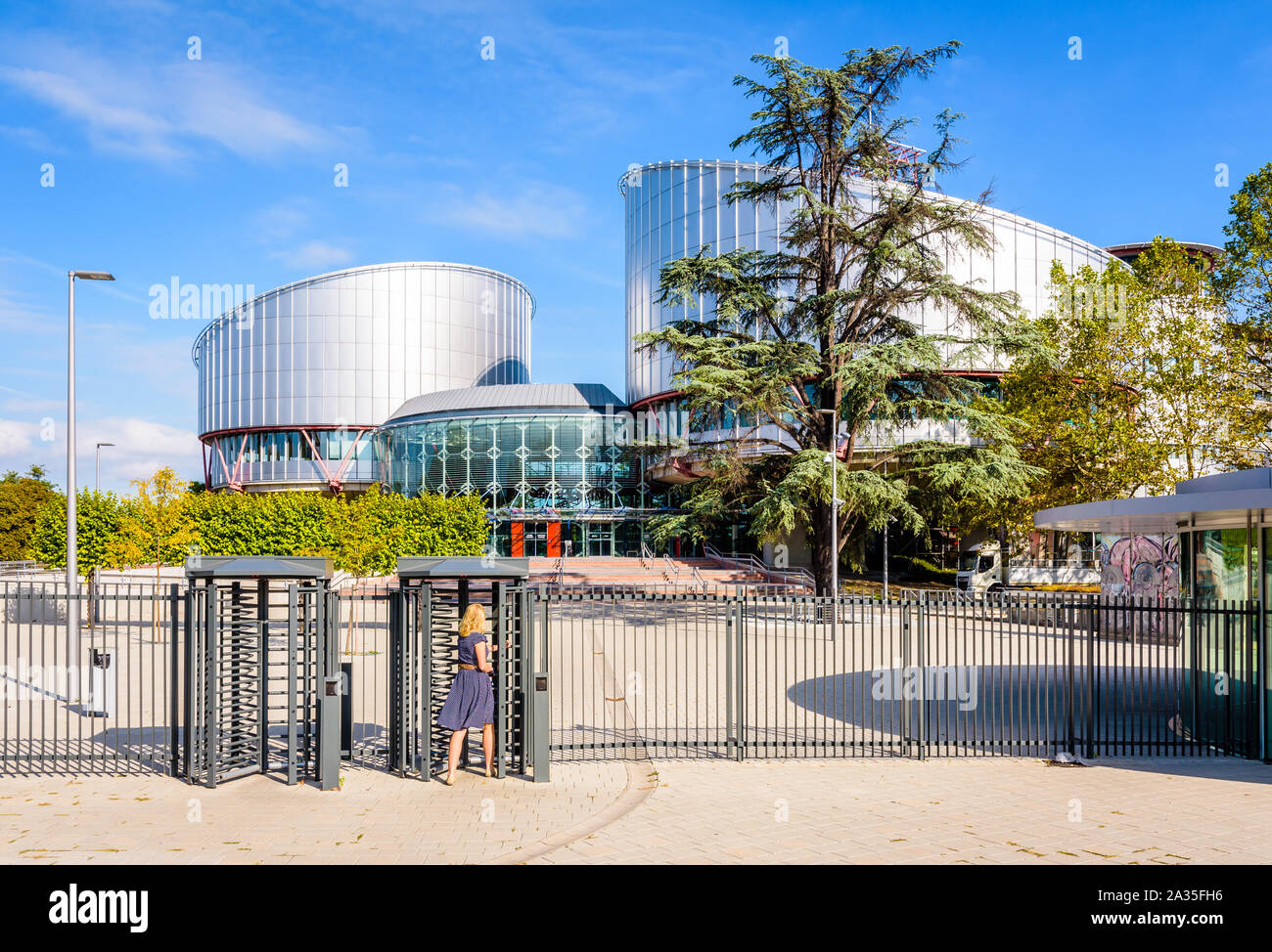 A woman in blue dress is passing the security turnstile to enter the building of the European Court of Human Rights in Strasbourg, France. Stock Photo