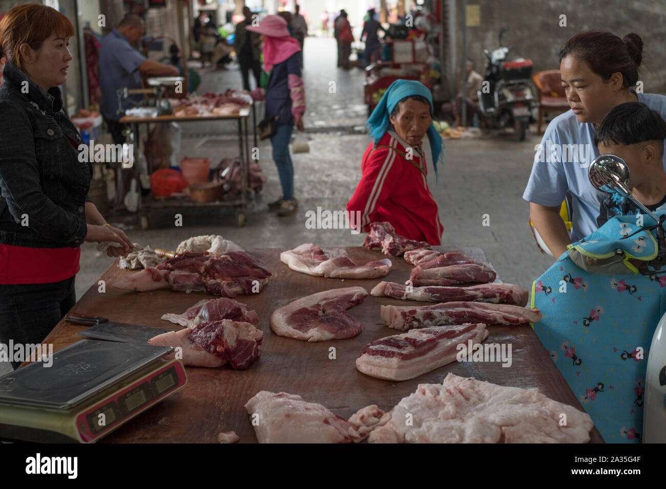 A Chinese vendor serves a customer at her pork stall in Jianshui, Yunnan, China. 25-Sep-2019 Stock Photo