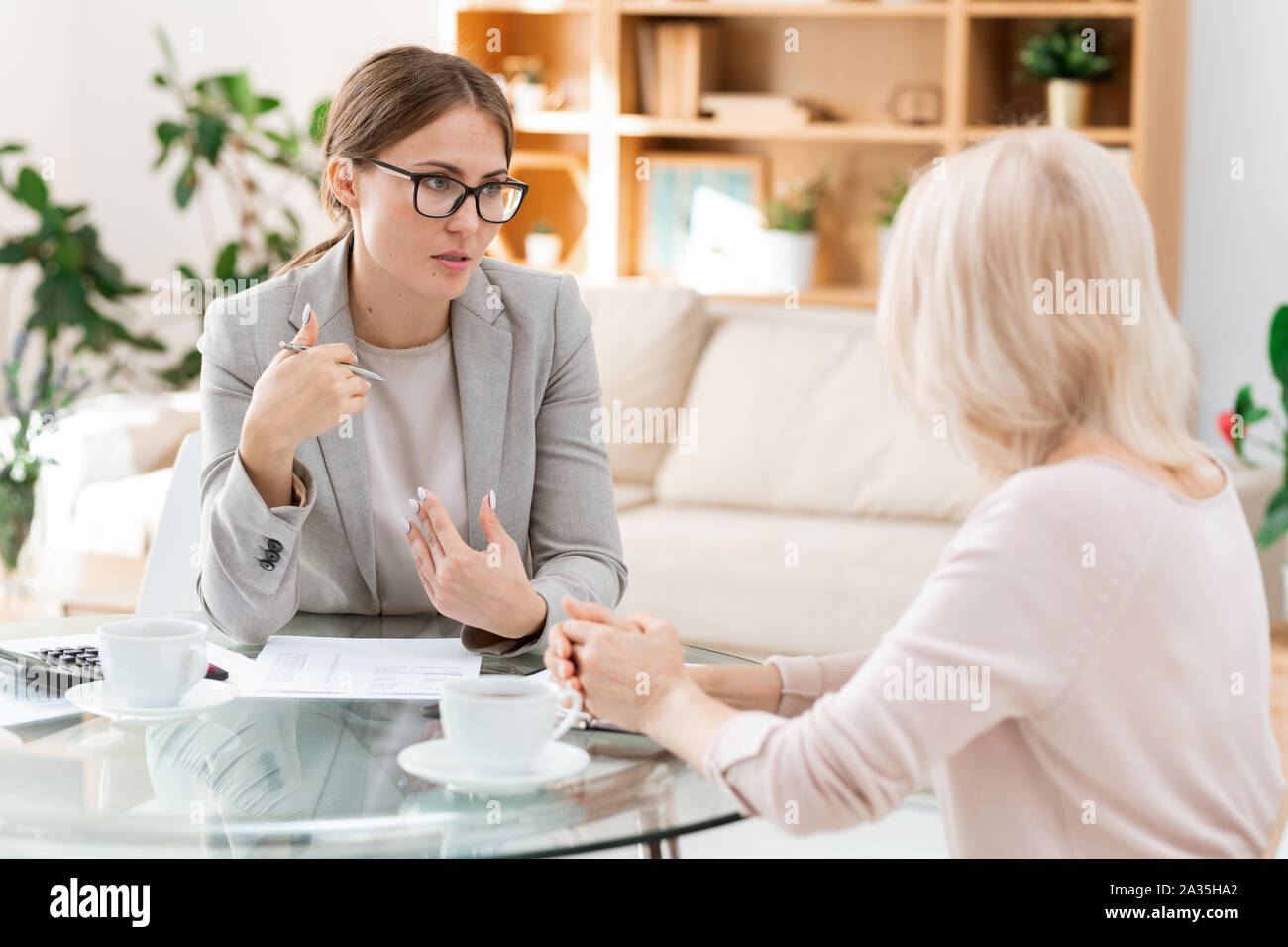 Young and mature accountants gathered by table for discussion of working points Stock Photo
