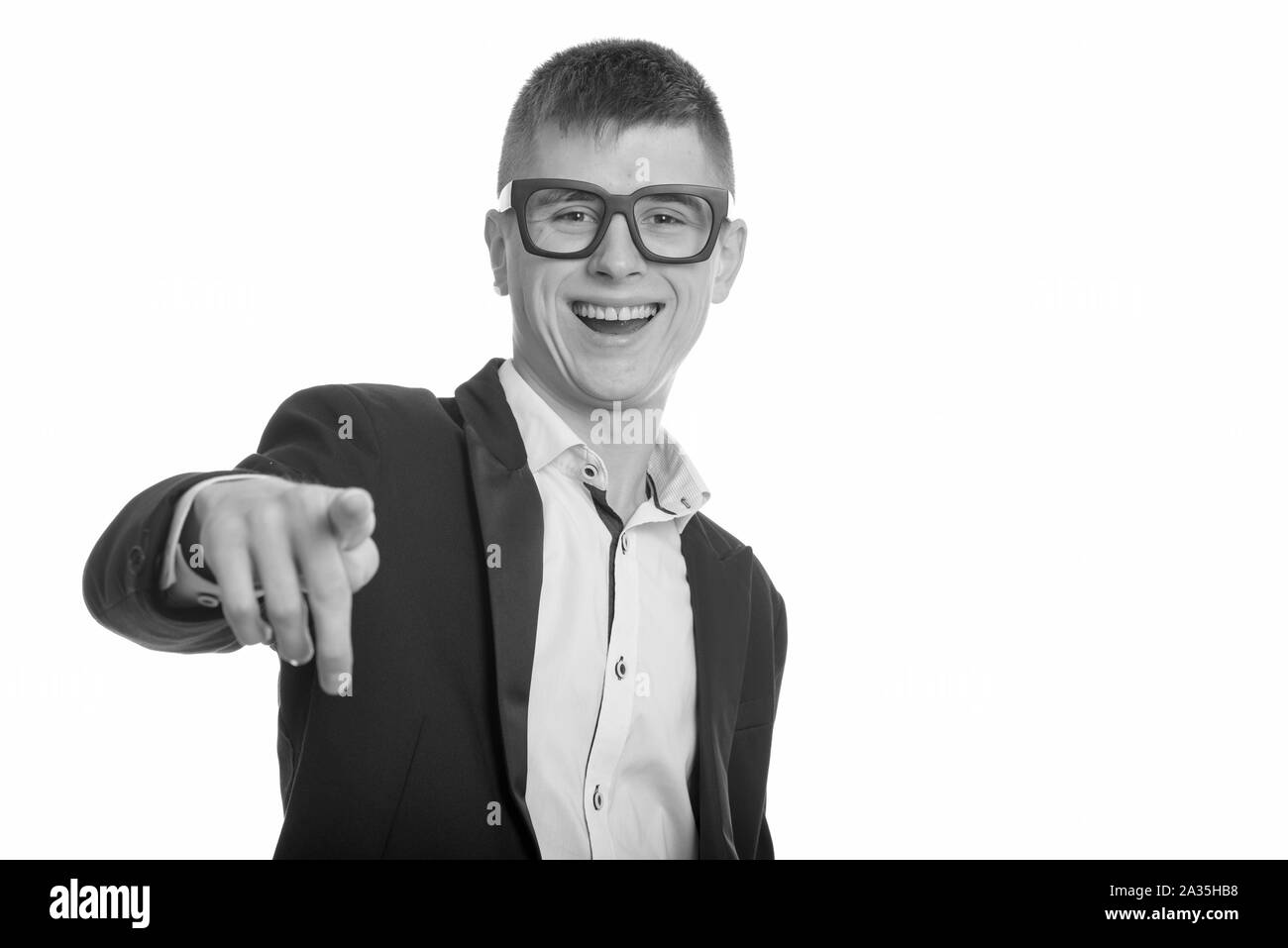 Studio shot of young happy businessman smiling and laughing while pointing finger at camera Stock Photo