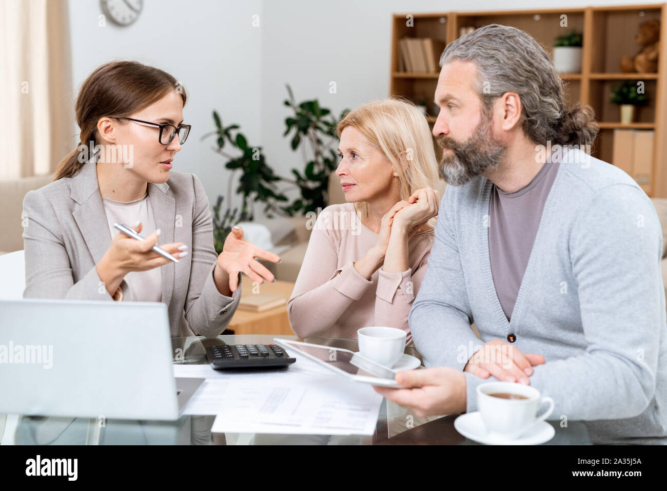 Mature couple and real estate agent discussing financial points Stock Photo