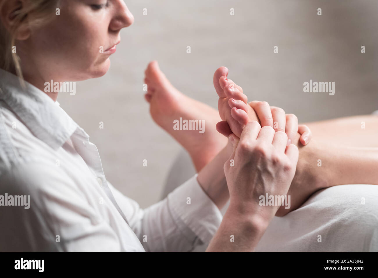 Professional female masseur giving reflexology massage to woman foot Stock Photo