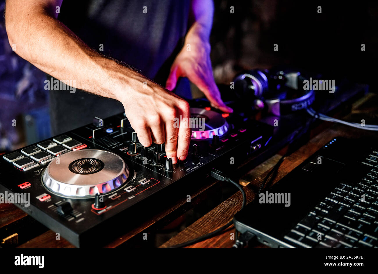 DJ plays live set and mixing music on turntable console at stage in the